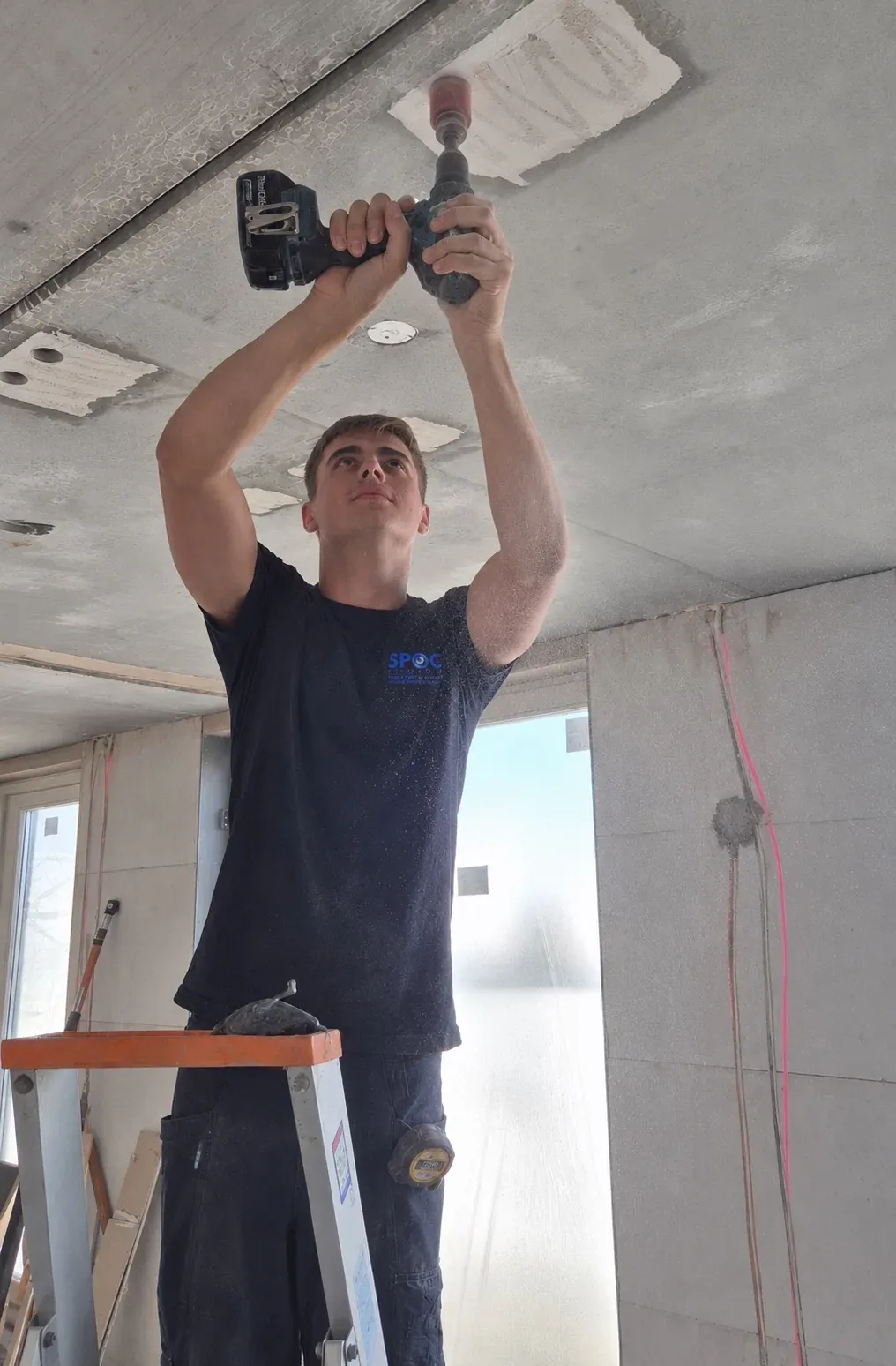 Keano Boumans van SPOC-Security monteert een detector aan een betonnen plafond